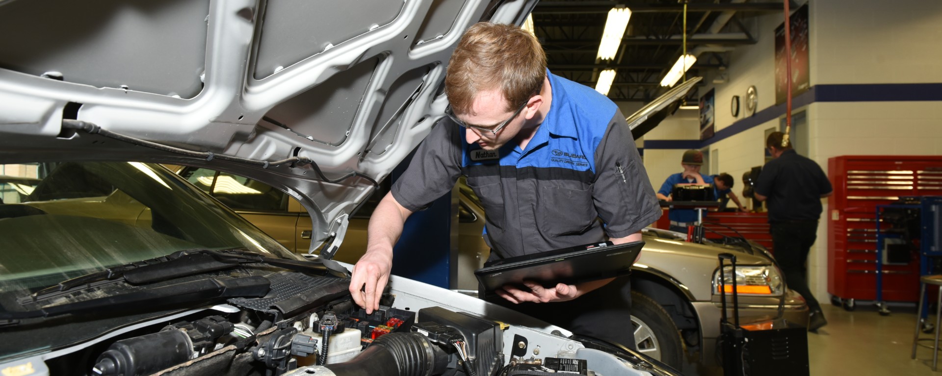 automotive student looking under the hood