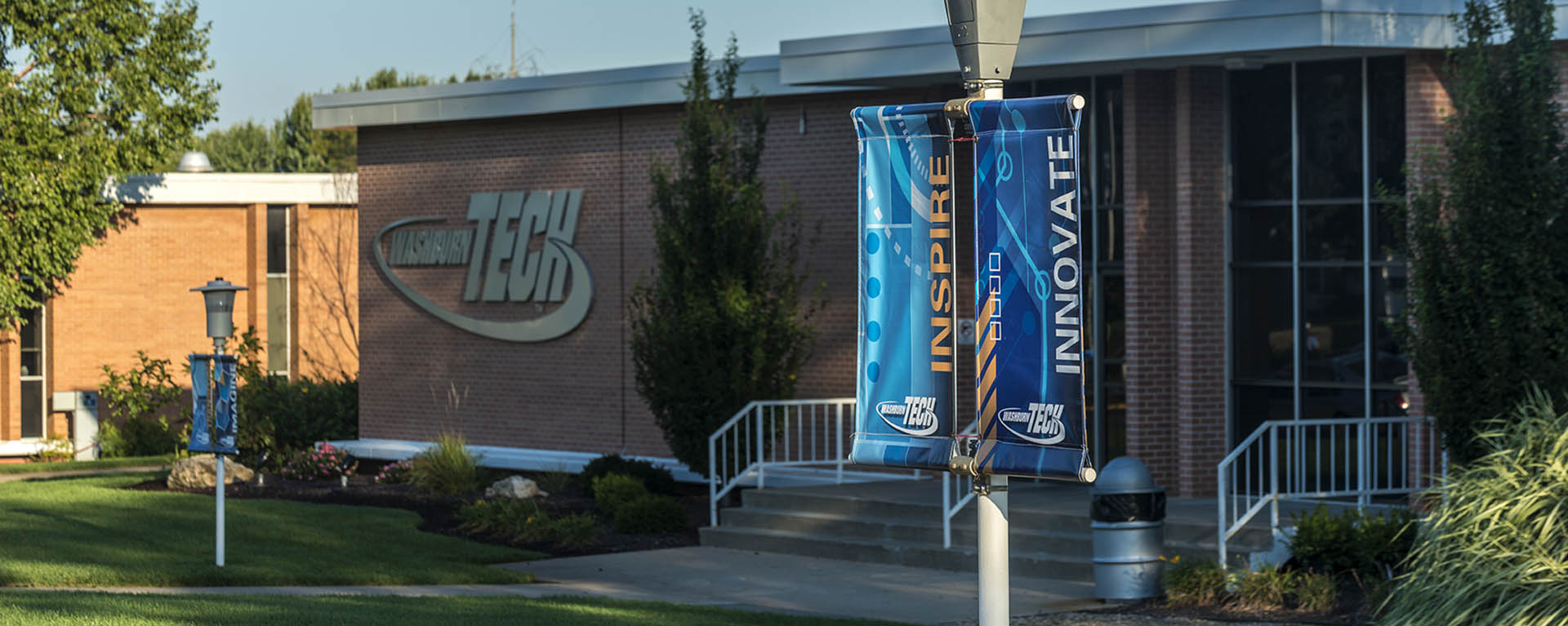 Two sign poles with Washburn Tech banners outside a building.