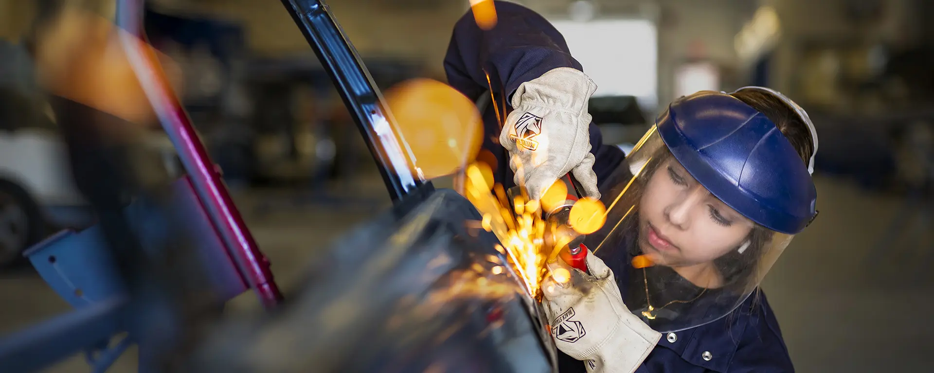 An Washburn Tech automotive student uses a grinder with sparks flying to make a repair.