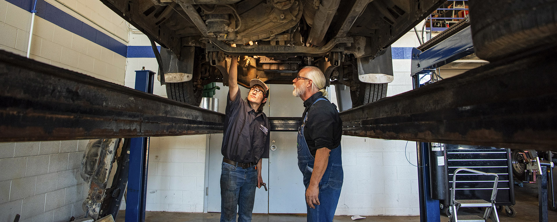 diesel student and instructor look under truck