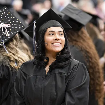 student smiling in cap-n-gown during graduation