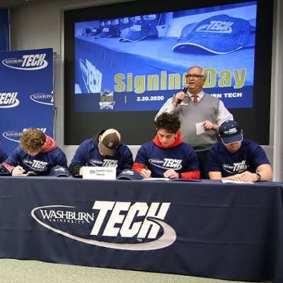 students at a table signing letter of intent