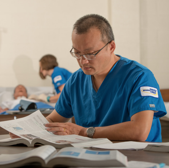 man reading books in nurse scrubs